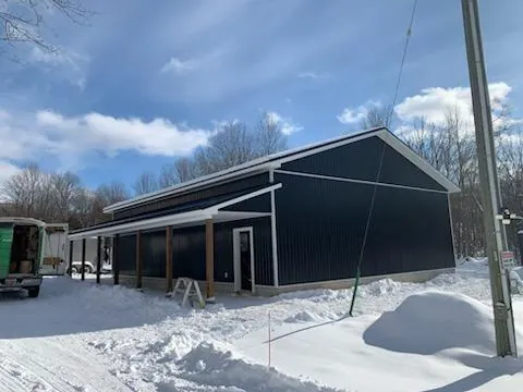 Navy steel clad farm building with a covered lean to built by CKThompson Contracting in Grey County
