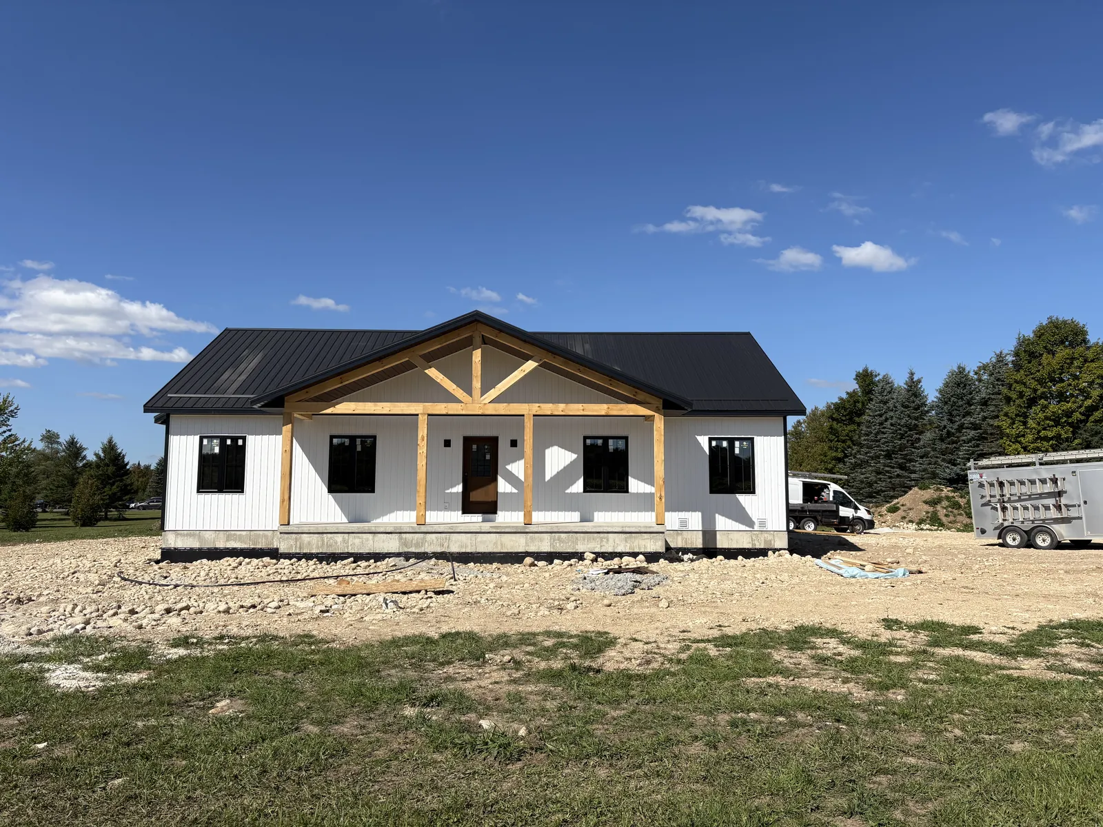 White board and batten custom home with a timber frame porch built by CKThompson Contracting in Grey County