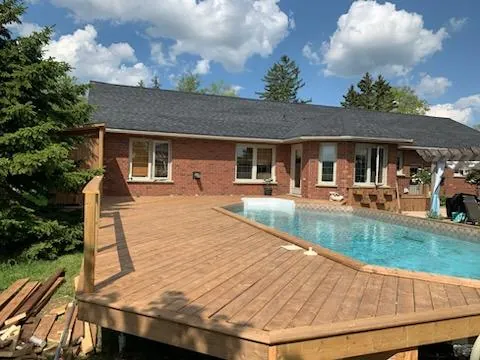 Wood pool deck behind a brick bungalow built by CKThompson Contracting in Grey County