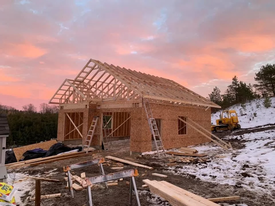 House framing at sunset with roof trusses being set by CKThompson Contracting
